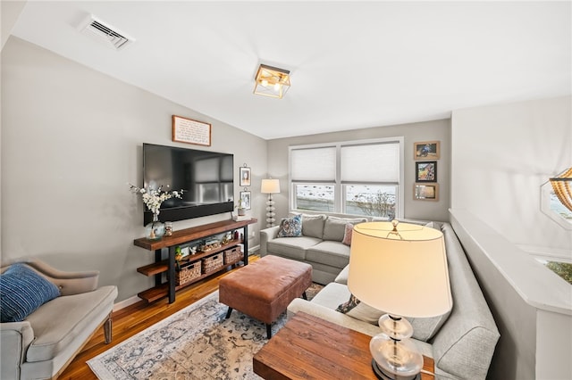 living area featuring baseboards, visible vents, and wood finished floors