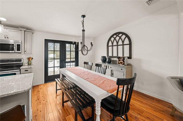 dining room with light wood-style floors, baseboards, visible vents, and french doors