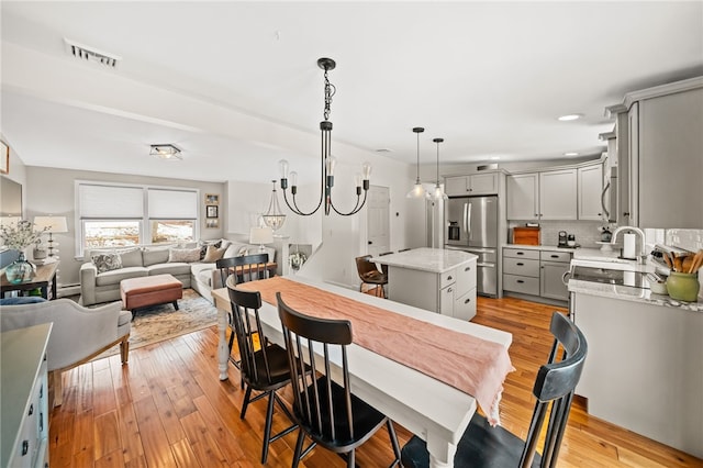 dining space featuring light wood finished floors, visible vents, and an inviting chandelier