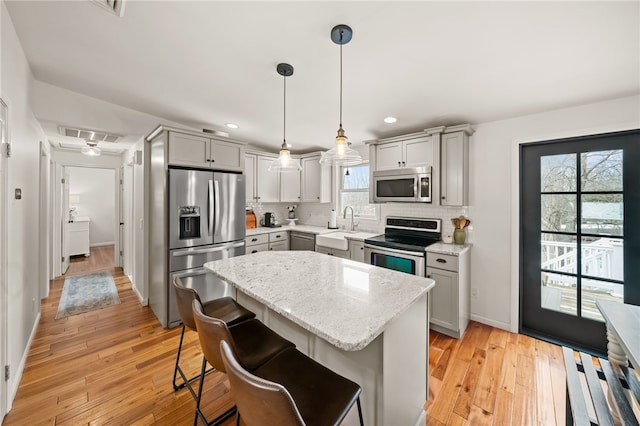 kitchen featuring appliances with stainless steel finishes, gray cabinets, light wood-style floors, and decorative backsplash