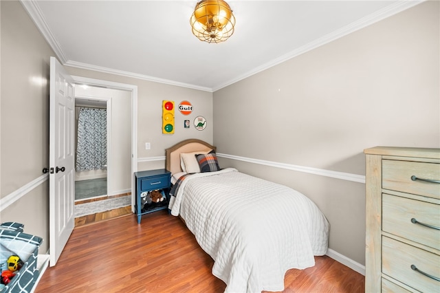 bedroom with crown molding, baseboards, and wood finished floors