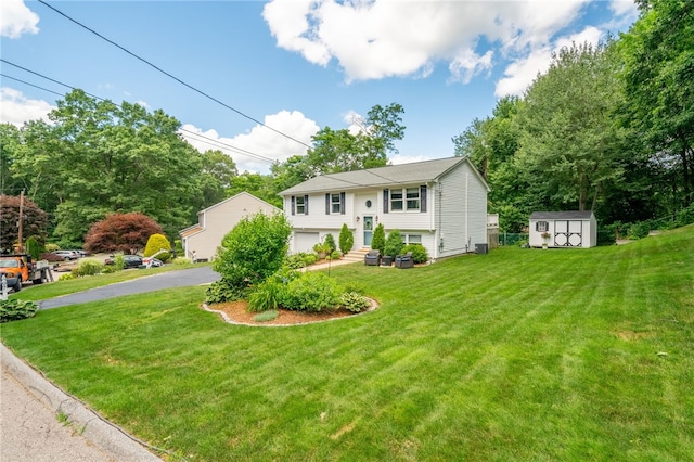 bi-level home featuring an attached garage, a shed, a front yard, an outbuilding, and driveway