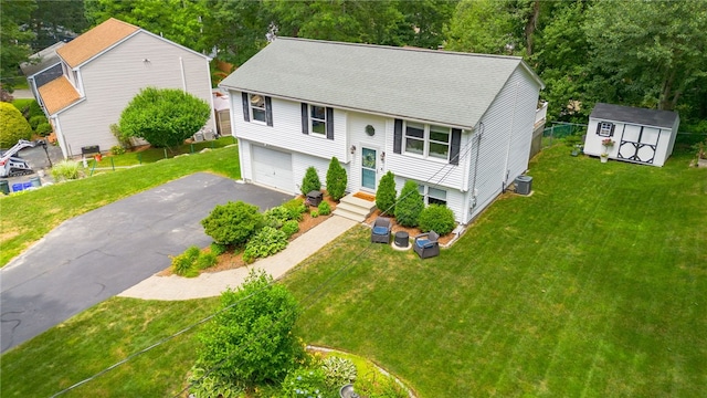 split foyer home with entry steps, aphalt driveway, central AC, a storage unit, and a front yard