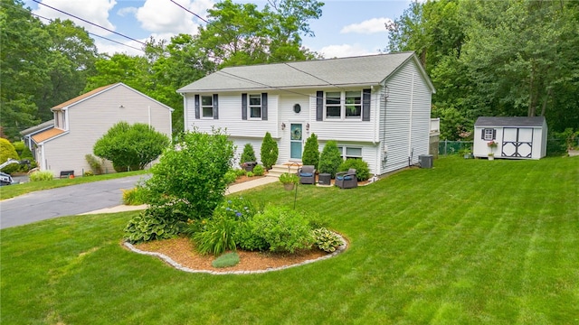 bi-level home featuring aphalt driveway, a storage unit, entry steps, an outdoor structure, and a front lawn