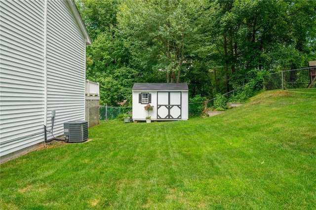 view of yard featuring a storage unit, a fenced backyard, central AC unit, and an outbuilding