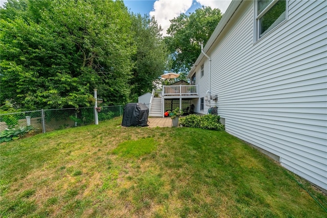 view of yard featuring a deck, fence, and stairs