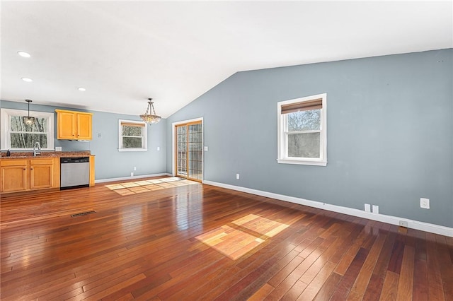 unfurnished living room featuring plenty of natural light, lofted ceiling, dark wood finished floors, and baseboards