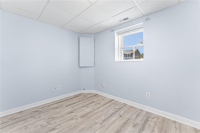 empty room featuring a drop ceiling, wood finished floors, visible vents, and baseboards