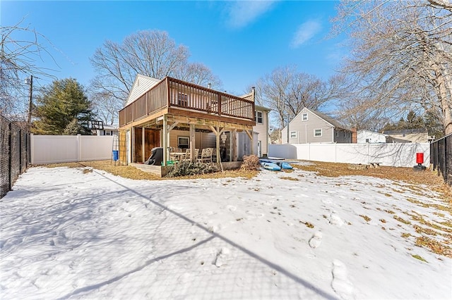 snow covered house featuring a fenced backyard and a wooden deck