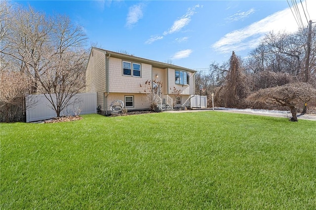 view of front of home featuring entry steps, fence, and a front lawn