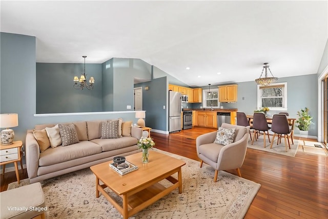 living room with vaulted ceiling, baseboards, hardwood / wood-style flooring, and an inviting chandelier