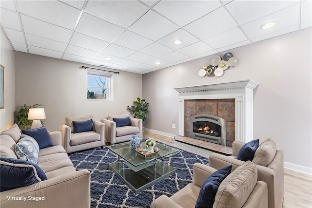 living area with baseboards, a tile fireplace, wood finished floors, a paneled ceiling, and recessed lighting