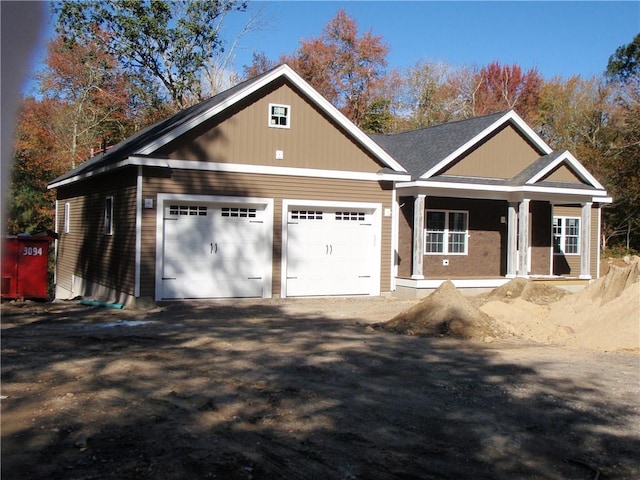 view of front facade featuring an attached garage, covered porch, and driveway