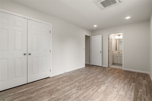 unfurnished bedroom featuring visible vents, baseboards, ensuite bathroom, wood finished floors, and a closet