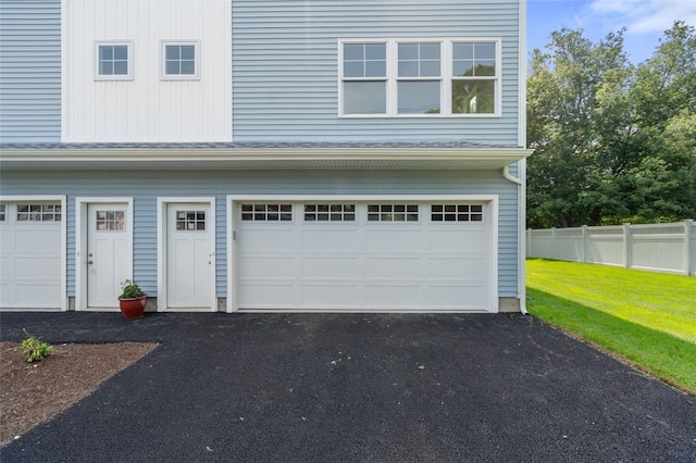 garage featuring aphalt driveway and fence