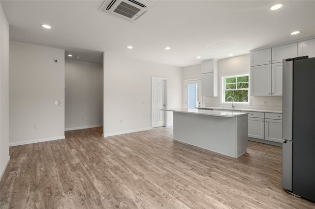 kitchen with visible vents, light wood-style floors, light countertops, and freestanding refrigerator