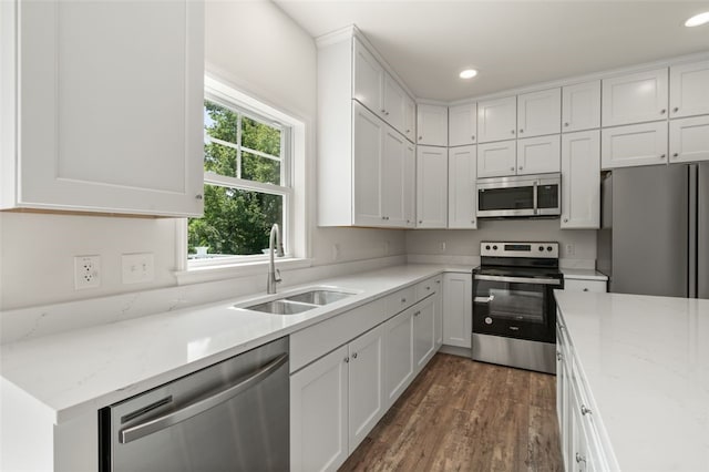 kitchen featuring recessed lighting, dark wood-style flooring, a sink, stainless steel appliances, and white cabinets