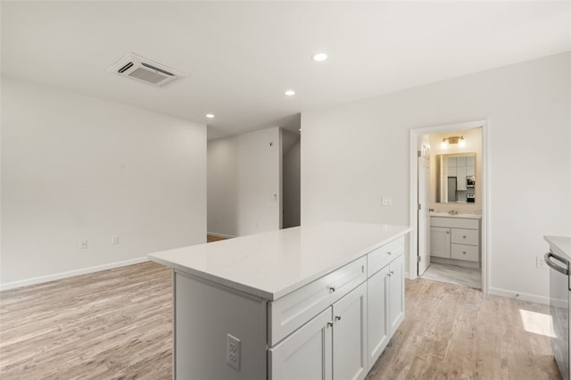 kitchen featuring visible vents, light countertops, white cabinets, light wood-type flooring, and a center island