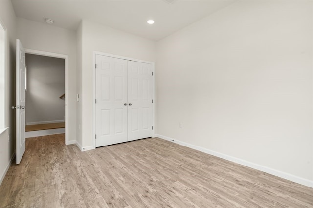 unfurnished bedroom featuring recessed lighting, a closet, baseboards, and light wood finished floors