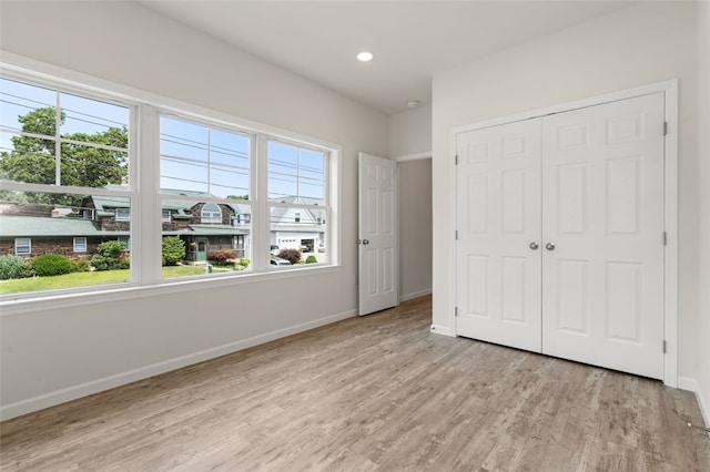 unfurnished bedroom featuring a closet, recessed lighting, baseboards, and wood finished floors