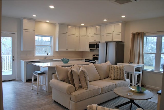 living room with visible vents, recessed lighting, light wood-type flooring, and baseboards