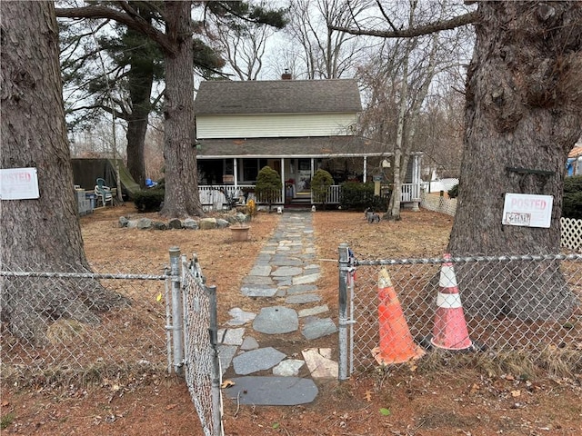 view of front facade featuring covered porch, a fenced front yard, a gate, and roof with shingles