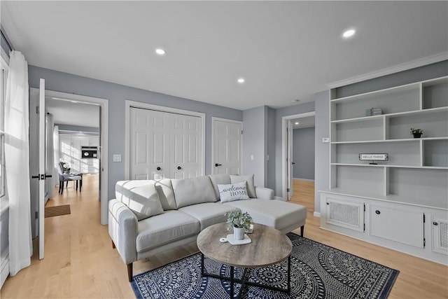 living room with light wood finished floors, built in features, and recessed lighting