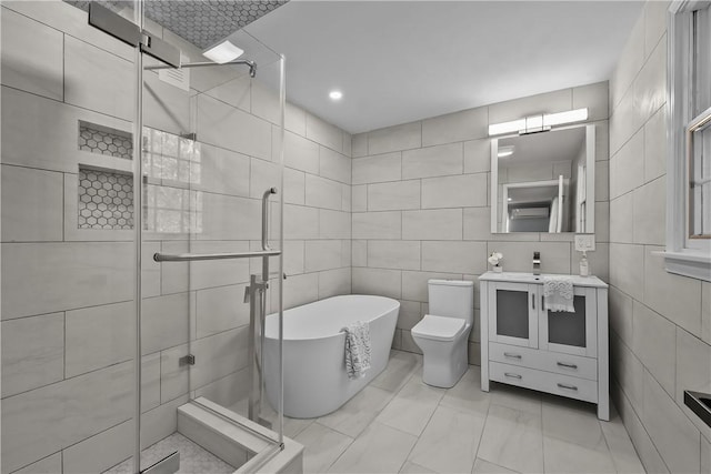 bathroom with a stall shower, a soaking tub, vanity, and tile walls