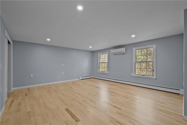 empty room with a baseboard heating unit, an AC wall unit, baseboards, and light wood finished floors