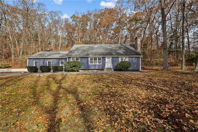 ranch-style home with a chimney and a front yard