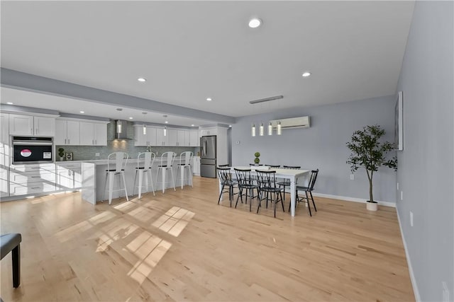 dining space featuring recessed lighting, light wood-style flooring, baseboards, and a wall mounted AC