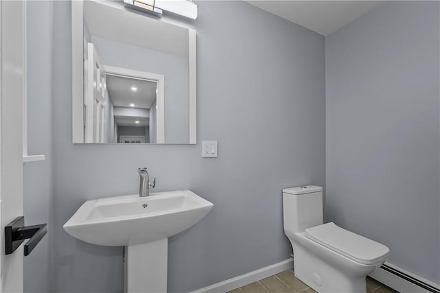 half bath featuring toilet, baseboards, and a baseboard heating unit