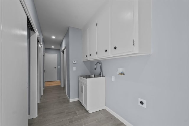 clothes washing area featuring hookup for a washing machine, light wood-style flooring, hookup for an electric dryer, a sink, and baseboards