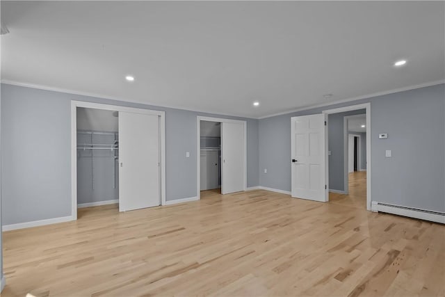 unfurnished bedroom featuring a baseboard radiator, light wood-style flooring, baseboards, multiple closets, and ornamental molding