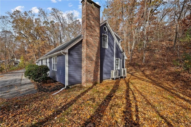 view of side of home featuring a chimney and central AC unit