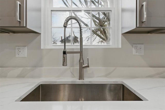 interior details featuring a sink and light stone countertops