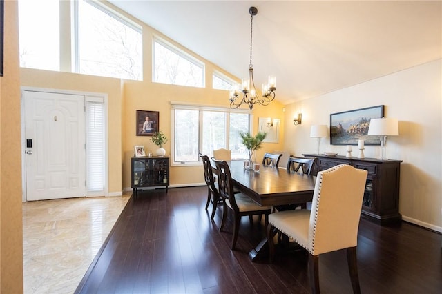 dining area featuring high vaulted ceiling, a notable chandelier, baseboards, and wood finished floors