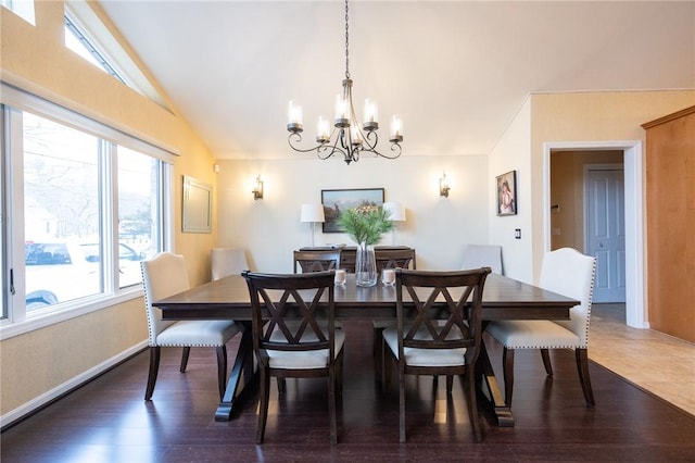 dining space with lofted ceiling, a notable chandelier, baseboards, and wood finished floors