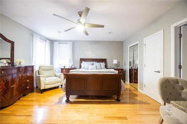 bedroom featuring ceiling fan, light wood-type flooring, and multiple closets