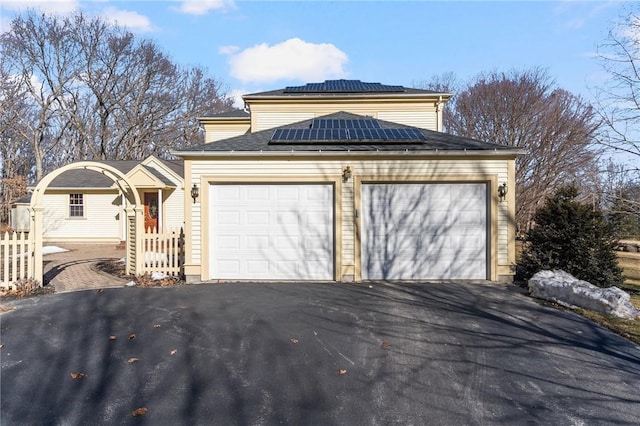 view of front of home featuring driveway, an attached garage, and roof mounted solar panels