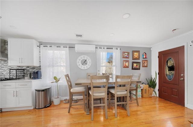 dining space featuring ornamental molding, light wood-type flooring, an AC wall unit, and visible vents