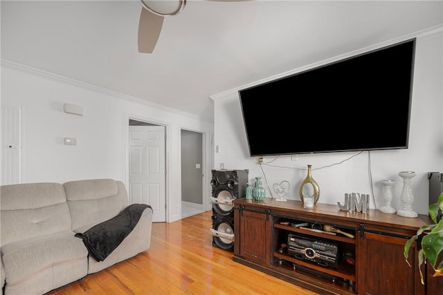 living room with light wood finished floors, ornamental molding, and a ceiling fan