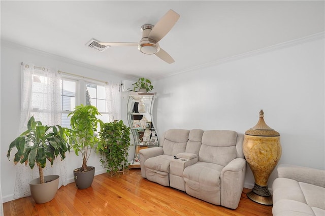 living room with a ceiling fan, visible vents, wood finished floors, and ornamental molding