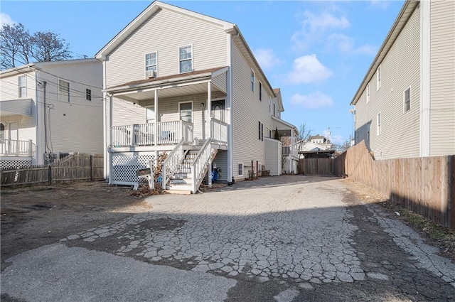 rear view of property with a porch, fence, and aphalt driveway