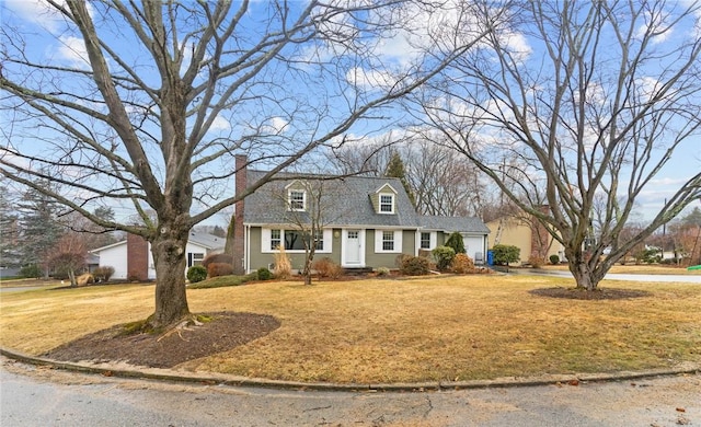 cape cod-style house featuring a garage, a chimney, and a front yard