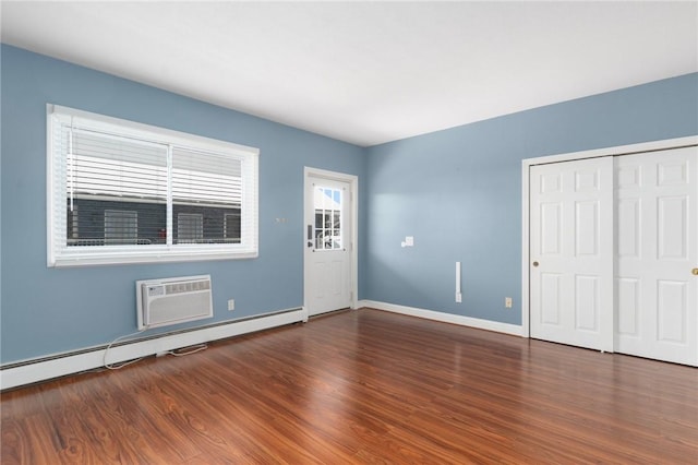 entrance foyer with a baseboard radiator, baseboards, wood finished floors, and a wall mounted AC