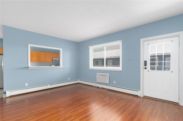 interior space featuring an AC wall unit, a baseboard radiator, wood finished floors, and baseboards