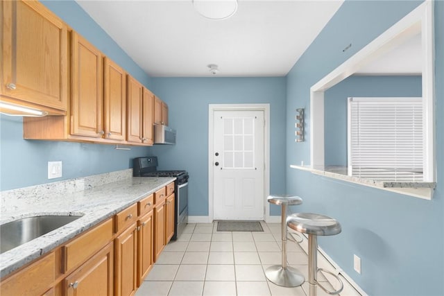 kitchen featuring light stone counters, light tile patterned floors, appliances with stainless steel finishes, baseboards, and exhaust hood