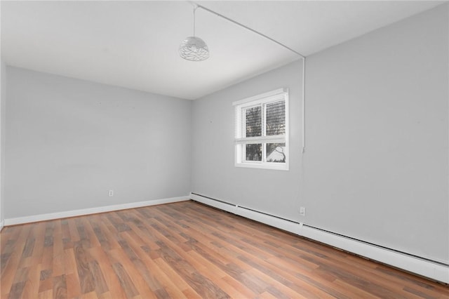 spare room featuring baseboards, baseboard heating, and wood finished floors