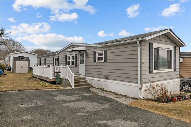 manufactured / mobile home with a storage unit, a deck, and an outbuilding